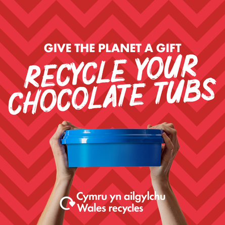 Blue plastic sweet tub held aloft by a pair of white hands with the slogan
